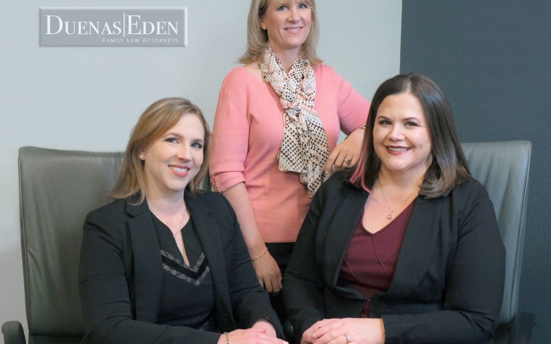 three women one standing two sitting legal office, pink sweater, black jackets, red blouse